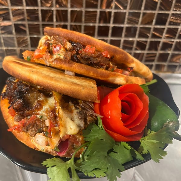 Two Harvest deli sandwiches filled with meat, cheese, and vegetables, garnished with a tomato rose.